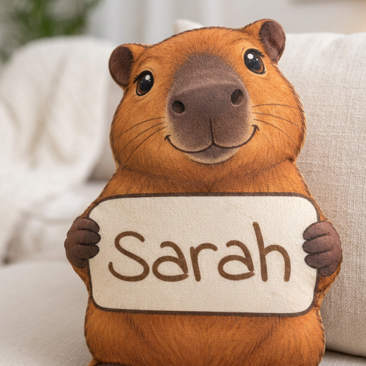 Close-up capybara plush pillow with white name sign reading Sarah.