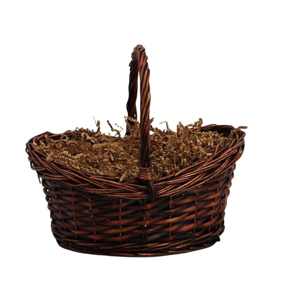 Woven wicker gift basket with dark shredded filler and loop handle.