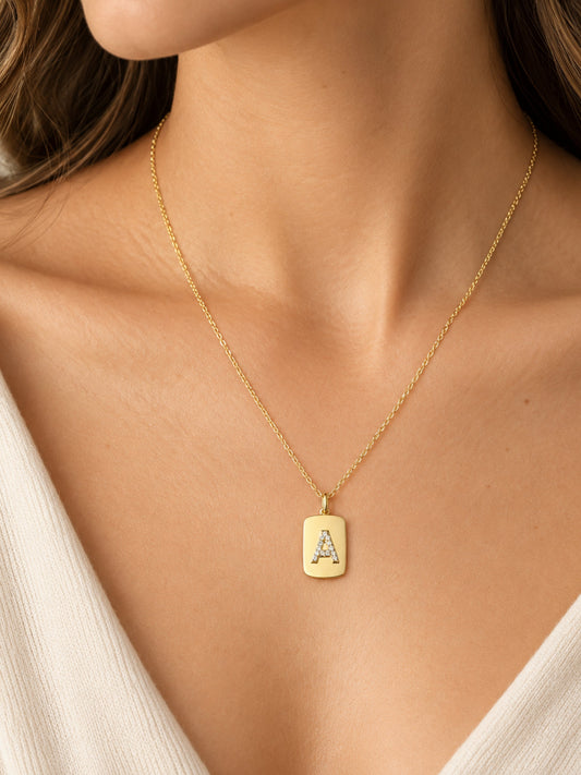 10k gold initial dog tag necklace pendant showing raised A with sapphire accents