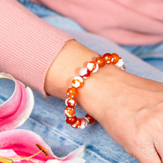 Orange and white beaded bracelet on wrist with stretchy round gemstone beads