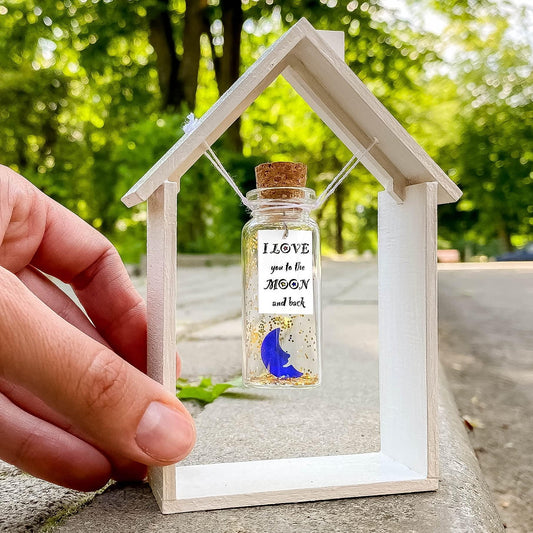 Hand holding house-shaped wooden frame with glass message bottle, blue moon print