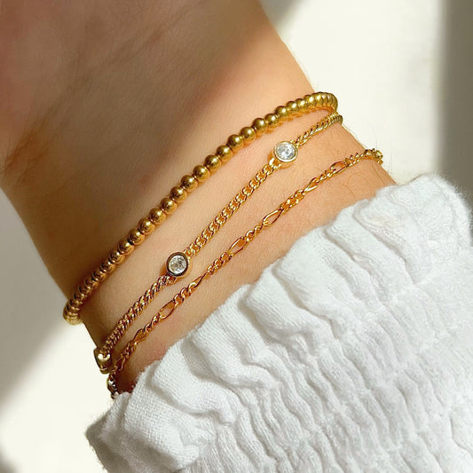 Gold bead elastic bracelet on wrist, stacked with other bangles