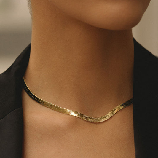 Gold herringbone chain necklace on neck with V-shaped link pattern