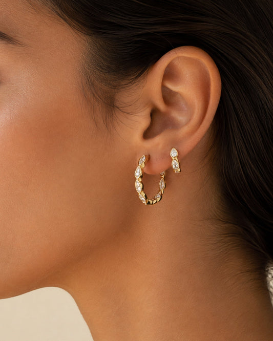 Gold-tone marquise hoop earrings with oval clear stones, close-up on ear
