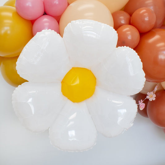 White daisy foil balloon with yellow center, close-up among pastel balloons