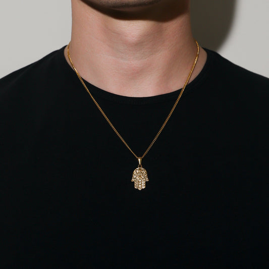 Gold curb chain necklace with small hamsa hand pendant worn at center of chest