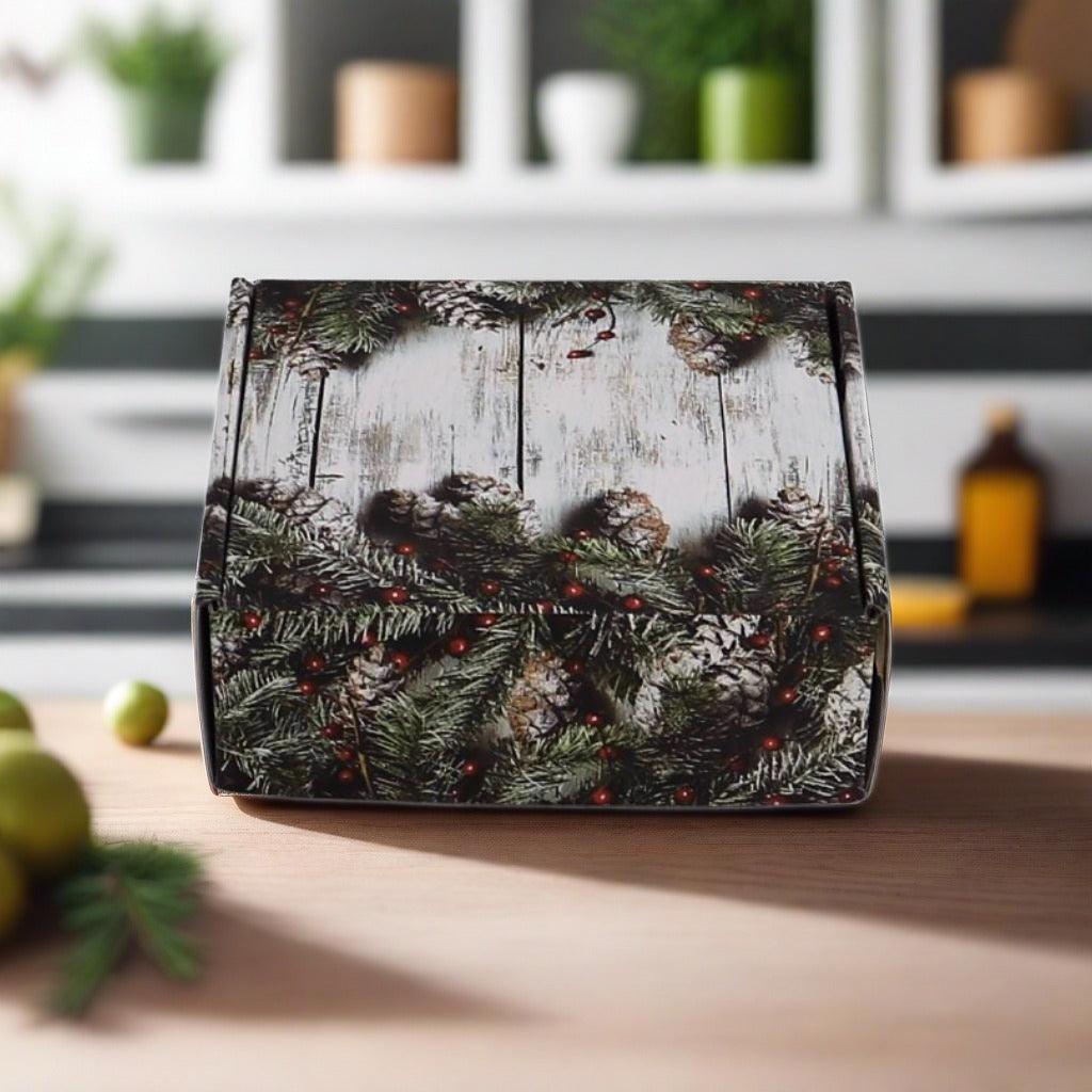 Closed holiday gift box with evergreen wreath and pinecone pattern on the lid.