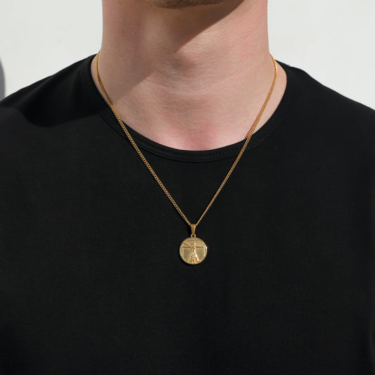 Gold-tone chain necklace with small round Vitruvian Man pendant on black shirt