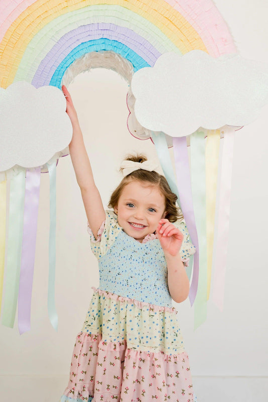 Piñata arcoíris tipo corazón con nubes blancas y tiras de colores pastel