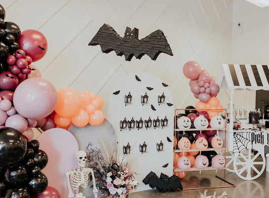 Bat-shaped piñata decoration on the wall, dark gray with hanging string