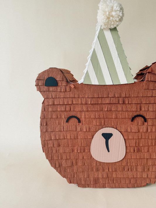 Close view of brown bear piñata candy holder with striped hat and nose emblem
