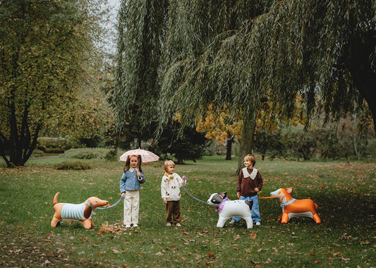 Dog-shaped character balloons standing outdoors among kids and fall trees