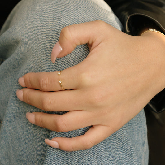 Gold-tone open bezel ring on hand, with two round clear stones