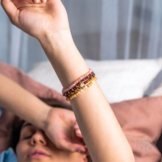 Beaded bracelet stack on wrist with multicolor stones and a round metal charm