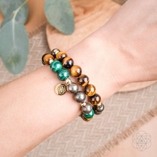 Pair of beaded bracelets on open palm: tiger’s eye and teal malachite beads