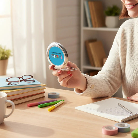 Silver glossy compact travel mirror held open by a person, with blue Teachers graphic