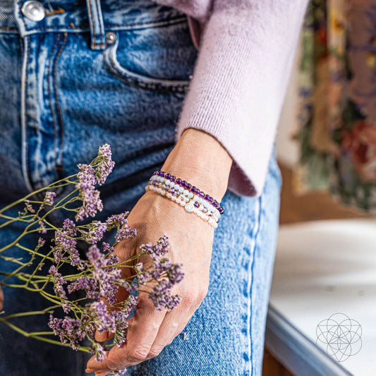 Beaded gemstone bracelet set on wrist with purple, rose, and light blue beads