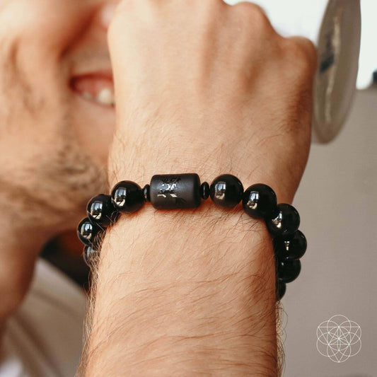 Black beaded bracelet worn on wrist, round beads with a dark etched center bead