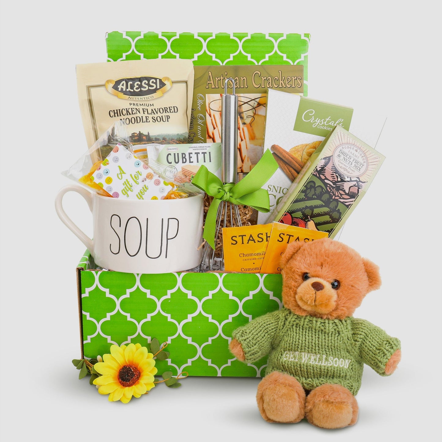 Cozy gift box with mug, crackers, plush teddy bear in green sweater and flower accents