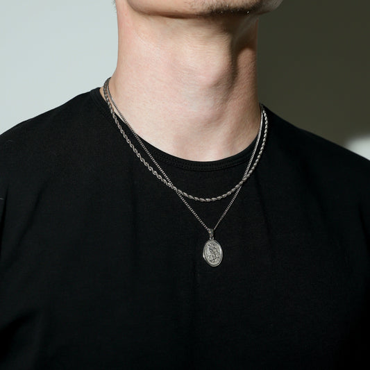 Silver rope chain set with oval Saint Michael pendant centered on neck.