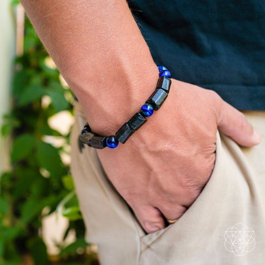 Blue and black beaded bracelet worn on wrist with dark rectangular stone pieces