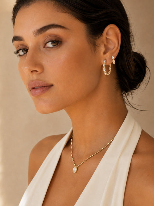 Gold ball-link necklace and teardrop pendant, worn by model in side profile
