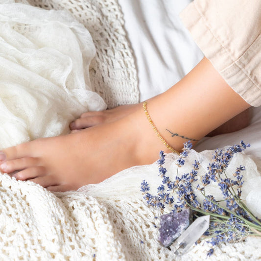 Gold beaded anklet on ankle with dangling charm pendant