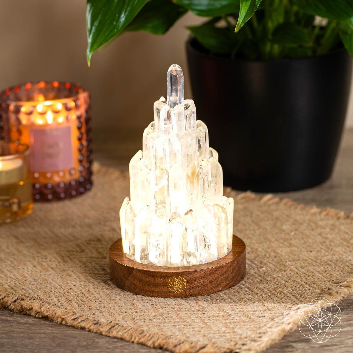 Glowing clear quartz tower lamp with round wooden base on textured mat