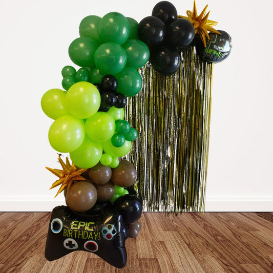 Game-themed balloon garland with green and black balloons, star topper, and gold tinsel
