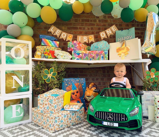 Green, gold, and white balloon garland above a birthday party display
