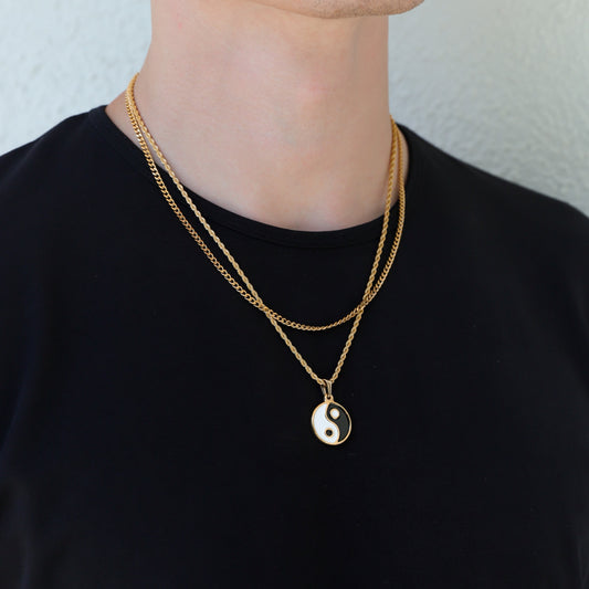 Gold yin-yang pendant necklace set with layered chain, worn on black shirt