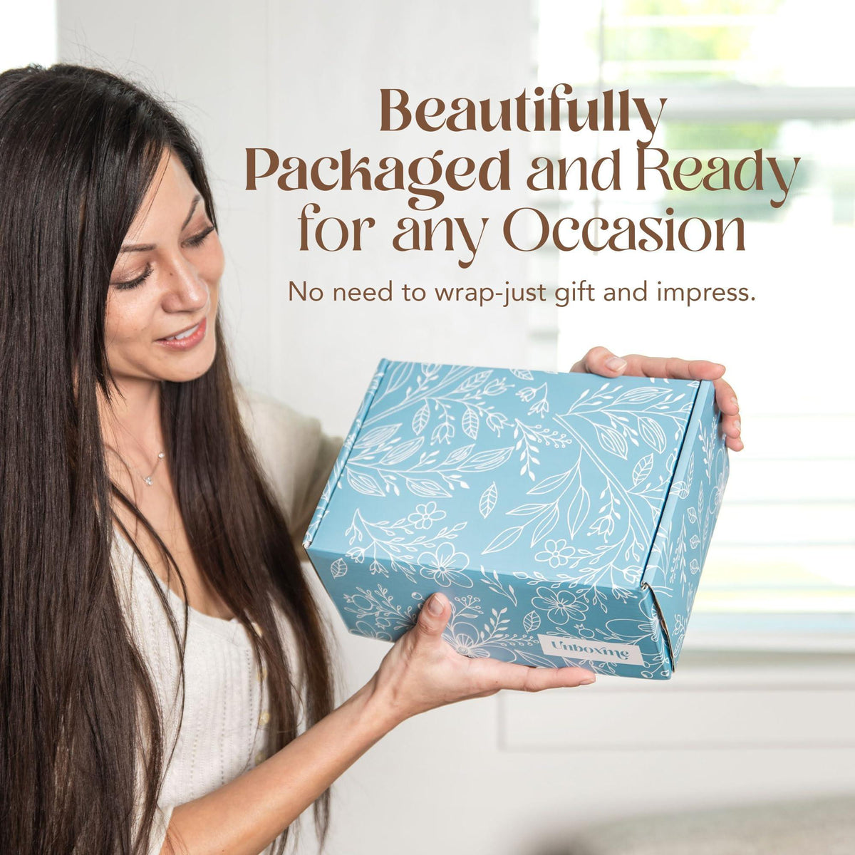 Self-care gift box held by woman, blue floral design on the package