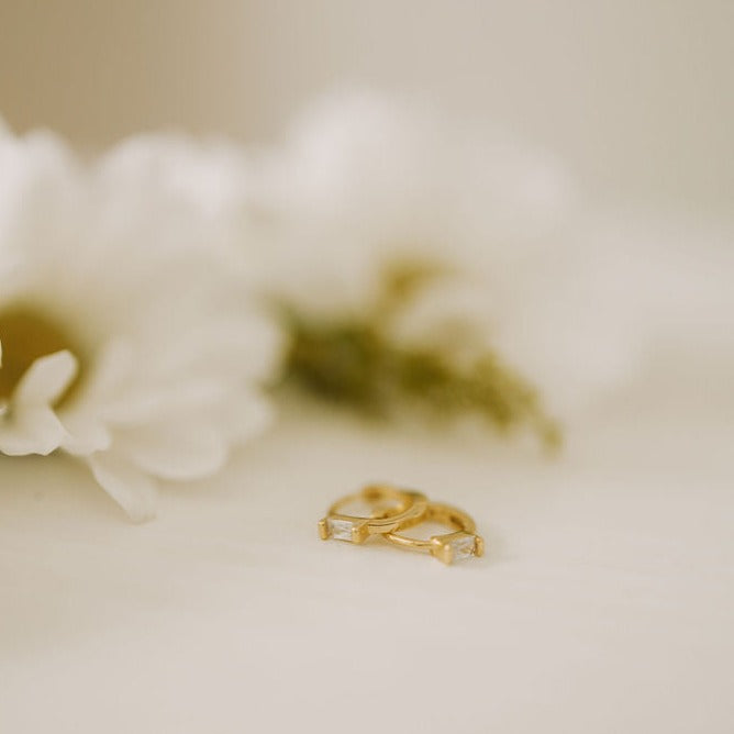 Gold baguette diamond mini hoop earrings, shown as a pair