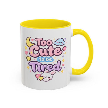 White mug with yellow rim and handle, “Too Cute to be Tired” text and bunny.