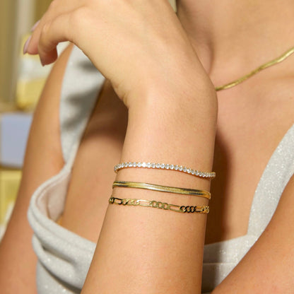 Gold-tone herringbone chain bracelet with stone-like accents on wrist