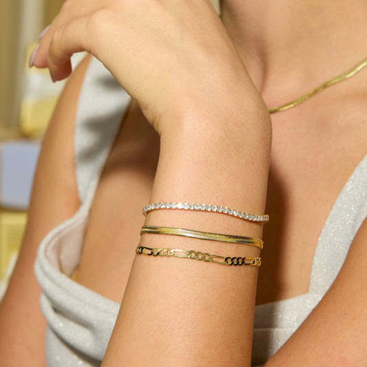 Gold figaro chain bracelet on wrist, interlocking link pattern