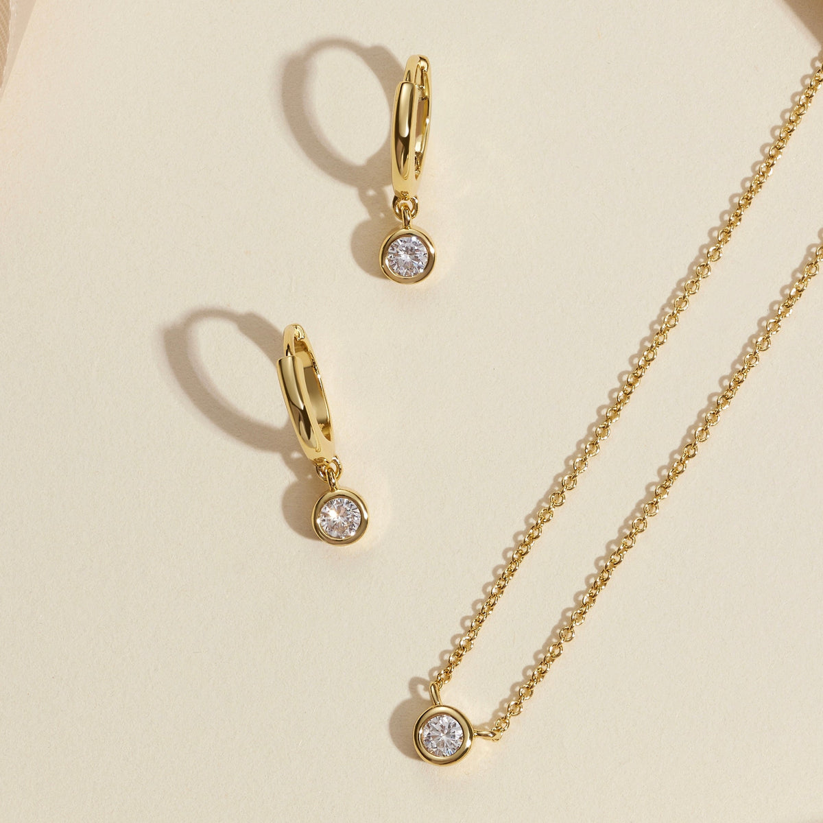Gold-tone layered necklace and hoop earrings with round bezel-set diamond pendants
