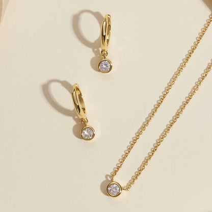 Gold-tone layered necklace and hoop earrings with round bezel-set diamond pendants