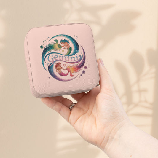 Pink compact jewelry travel case with Gemini graphic and zipper closure, held in hand