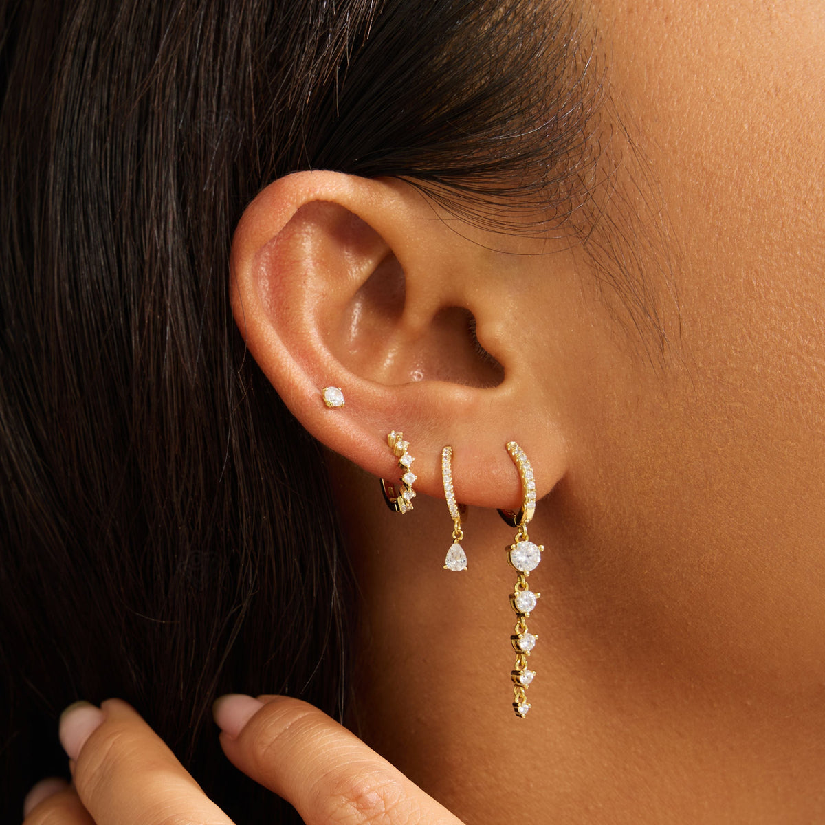 Close-up of gold hoop earrings with stacked round clear stones along the drop