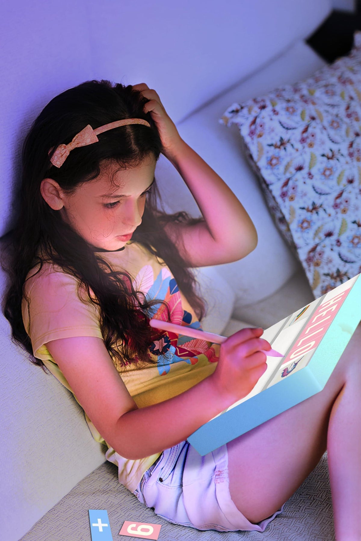 Child writing with a purple LED light box using colored letter tiles