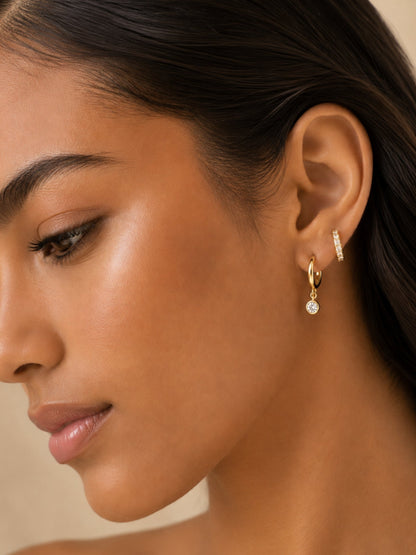Gold diamond huggie hoop and small diamond drop earrings on a side profile
