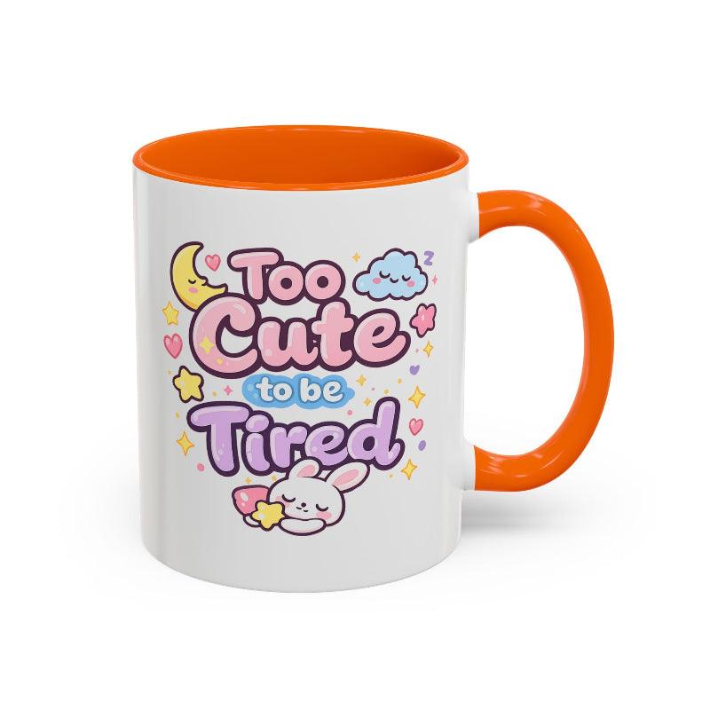 White mug with orange rim and handle, “Too Cute to be Tired” text and bunny.