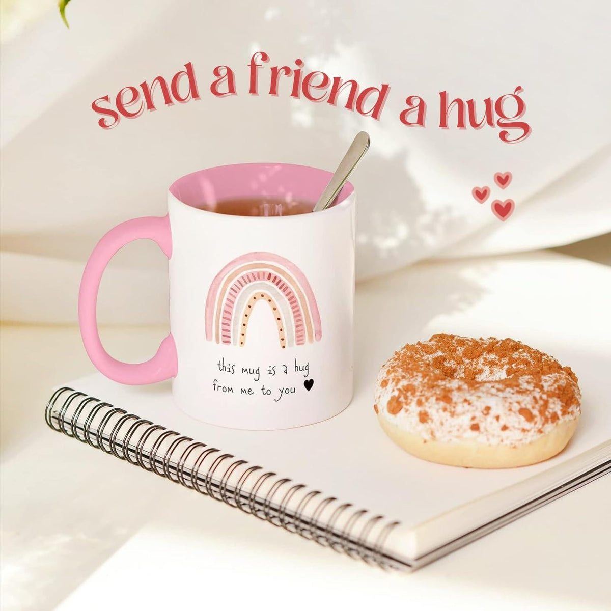 White ceramic mug with pink handle, rainbow hug graphic, and gift-ready message