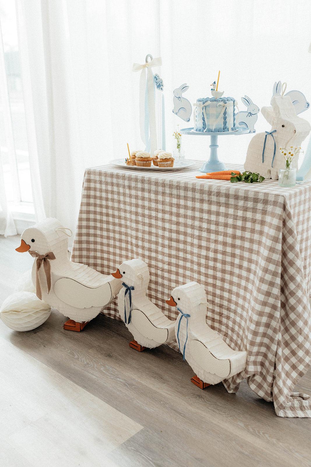 Duck piñata display: white duck with blue bow, orange feet and round paper body