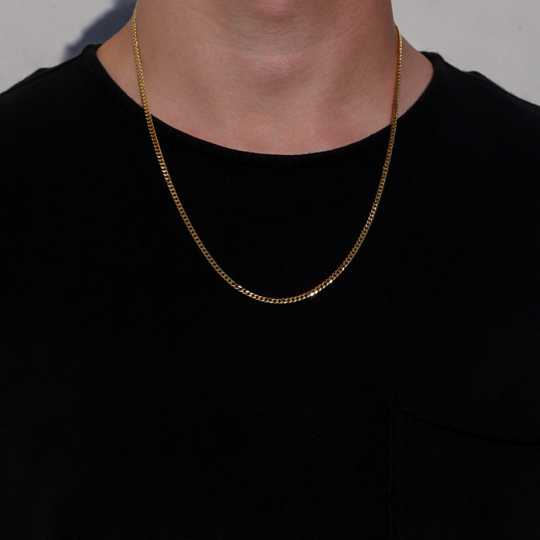 Gold Cuban link chain necklace on a model, featuring small interlocking links.