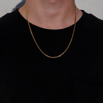 Gold Cuban link chain necklace on a model, featuring small interlocking links.