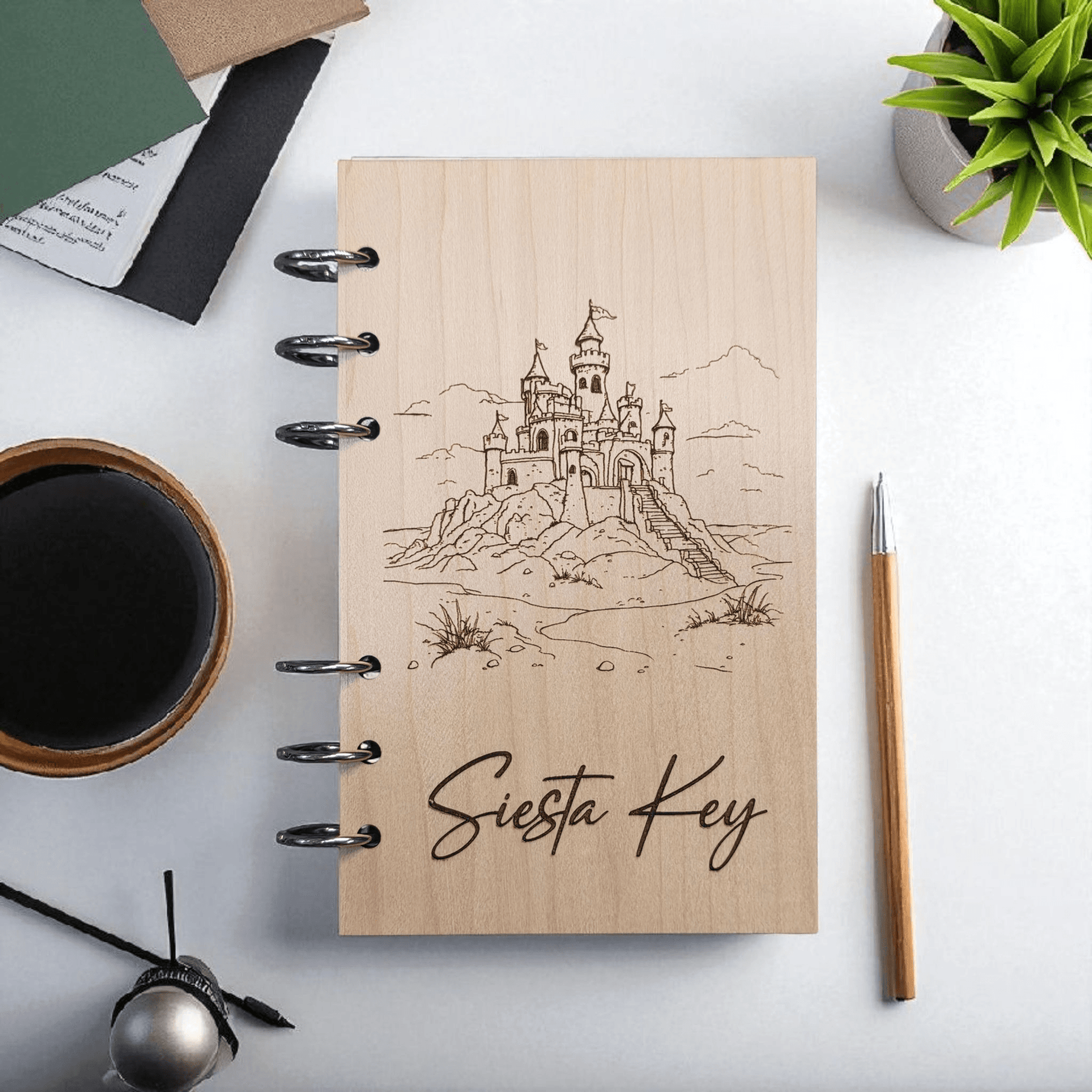 A6 refillable notebook, light tan cover with black spiral rings and line-art Siesta Key castle