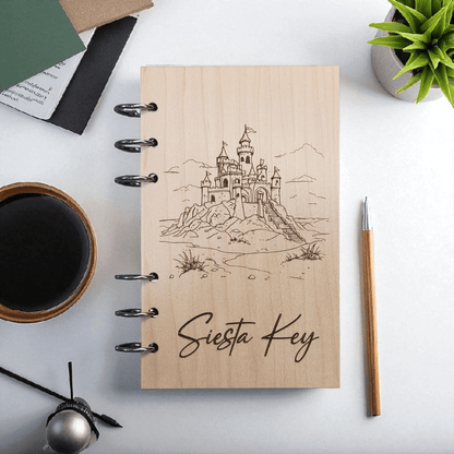 A6 refillable notebook, light tan cover with black spiral rings and line-art Siesta Key castle