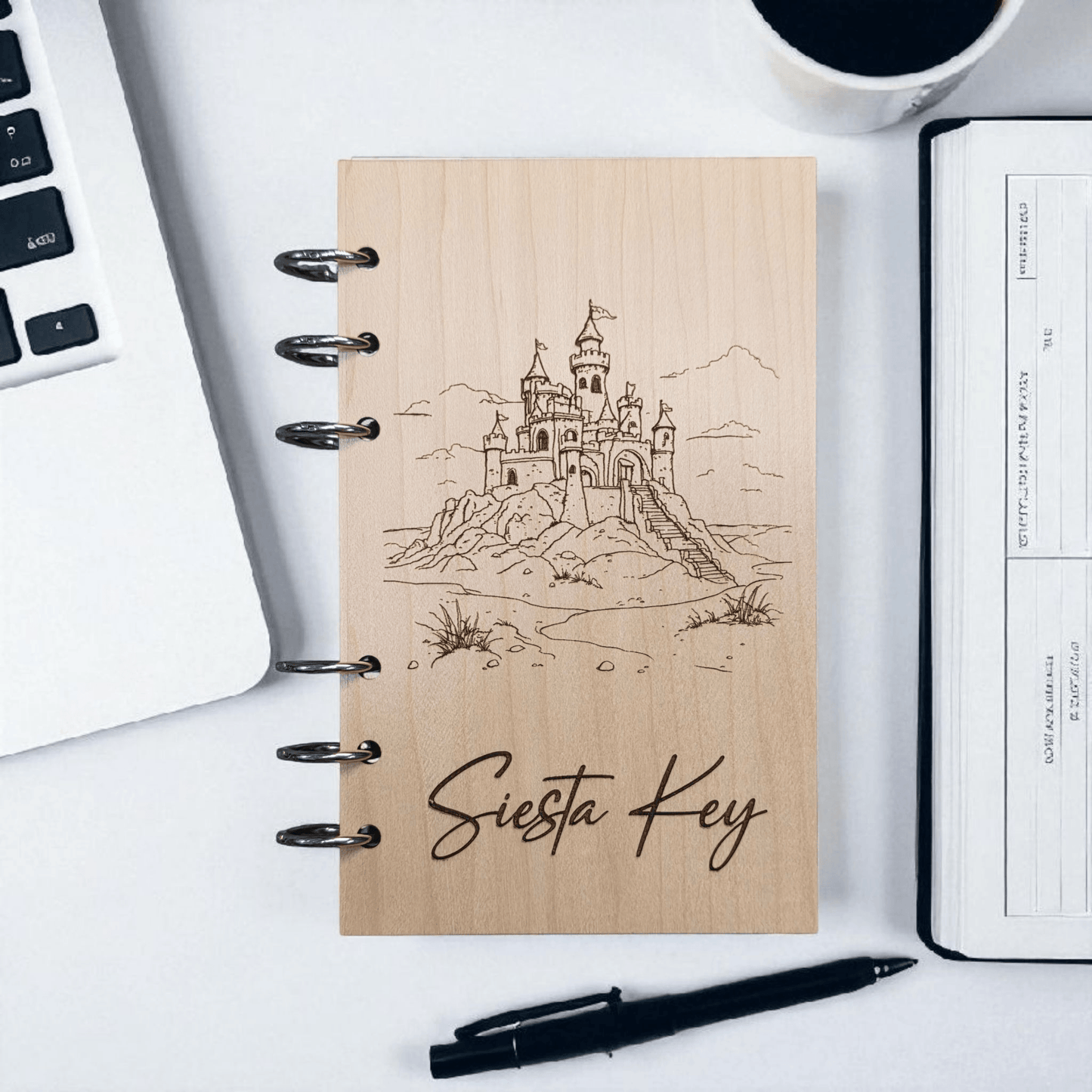 A6 refillable notebook with light tan cover, black spiral binding rings, line-art castle design